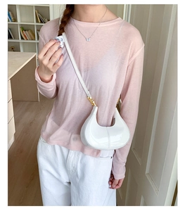 Detailed view of white patent leather crescent crossbody bag with gold metal hardware