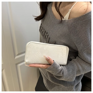 Close-up of a white sequin wallet with snake skin texture held by a model
