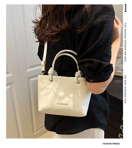 Detail of white snakeskin texture small square bag with gold FASHION lettering