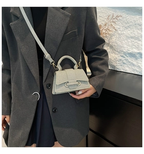 Mini sac à bandoulière en tissu gris texturé avec boucle épaisse porté par un mannequin