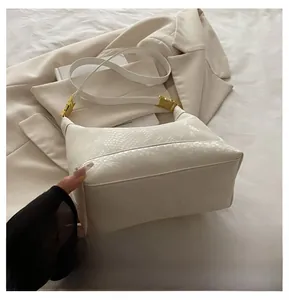 Detail of off-white shoulder bag featuring faux snake texture and gold metal buckle