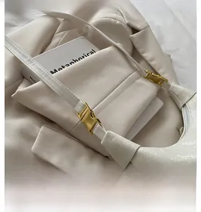 Detail of gold metal buckle and snake-embossed ivory faux leather on shoulder bag