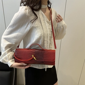 Elegant red crocodile texture handbag with gold metal clasp shown on model
