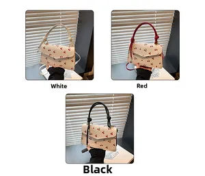 Detailed view of women's cherry print handbags in white, red, and black with crossbody straps