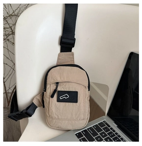 Detail of minimalist nylon crossbody bag with adjustable strap on a chair