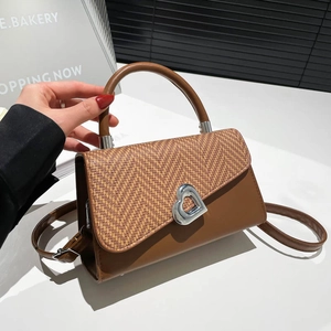 Brown patchwork handbag with woven texture, heart-shaped silver lock, and crossbody strap