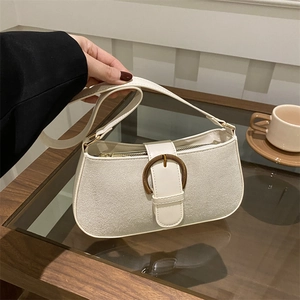 Chic cream underarm bag with vintage bronze D-buckle shown in a stylish cafe setting