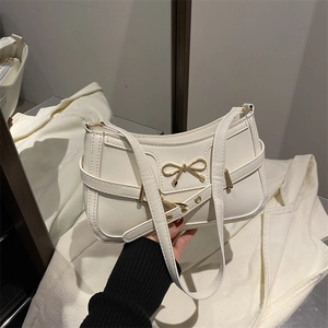 Elegant cream bow shoulder bag with gold metal hardware and structured leather finish
