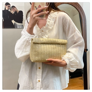 Dettaglio della pochette a busta in paglia intrecciata beige con trama e chiusura
