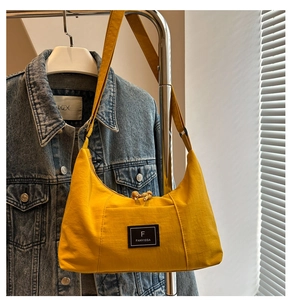 Detailed macro shot of a bright yellow canvas shoulder bag with a square brand label