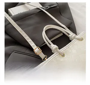 Close-up of white embossed leather handbag featuring luxury gold metal ring and handle detail