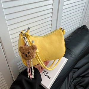 Fashionable yellow faux leather shoulder bag with plush bear charm and sleek design