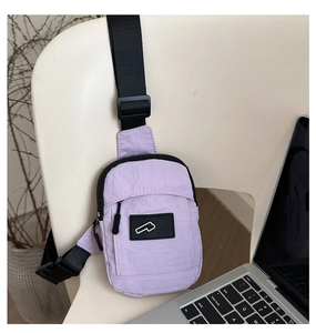 Detail view of the purple nylon mini chest bag showing its wrinkled texture and zipper pocket