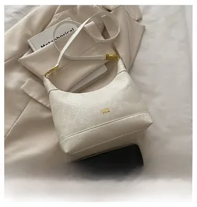 Detailed close-up of white embossed faux-snake leather hobo bag with gold COIR logo