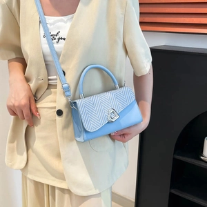 Vintage light blue handbag with herringbone flap and heart-shaped buckle on beige suit