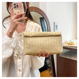 Detailed view of woven straw envelope clutch with natural fiber texture for summer