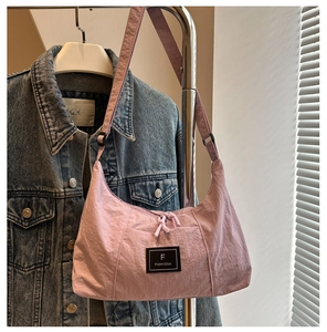 Close-up of a purple crescent canvas bag hanging on a hanger against a denim jacket