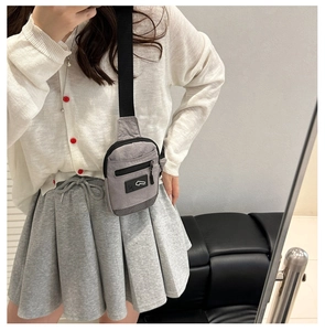 Détail d'un sac bandoulière gris en nylon avec poche zippée et sangle ajustable