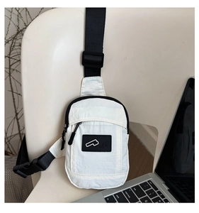 Detail of white nylon chest bag with black adjustable strap and logo on a chair