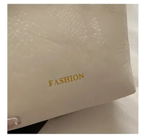 Detail of cream woven tote featuring snakeskin embossing and golden Fashion lettering