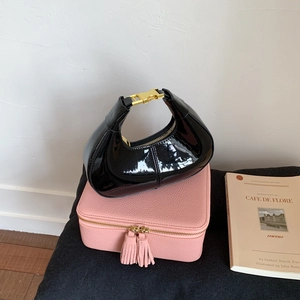 Sac hobo croissant en cuir verni noir avec boucle dorée sur boîte en cuir rose texturé