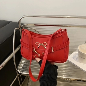 Fashionable red underarm bag with a gold bow buckle and a sleek vintage baguette silhouette