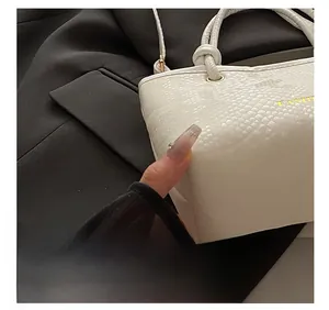Detailed macro view of white crocodile texture leather and golden metal clasp on handbag