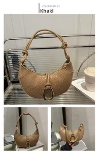 Detail of khaki woven crescent bag featuring a U-shaped buckle and twisted shoulder strap