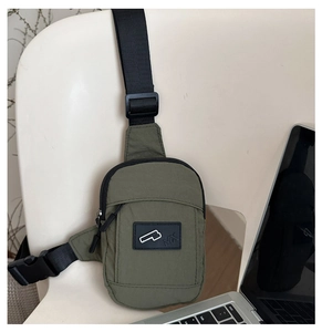 Detail of army green nylon chest bag featuring adjustable strap and black logo patch