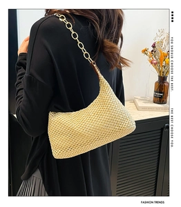 Detailed view of beige straw woven bag with a chunky gold chain strap for beach vacations
