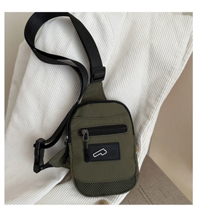 Détail de la sacoche en nylon vert armée avec poche zippée avant et écusson logo MK