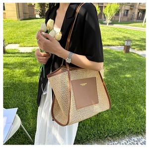 Detail of woven straw tote bag featuring brown leather trim and fashion brand tag