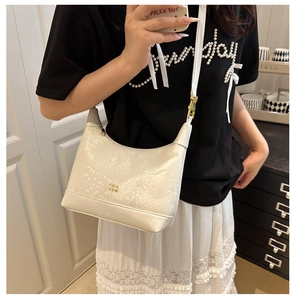 Close-up of white semi-circle shoulder bag featuring embossed snakeskin texture and gold logo