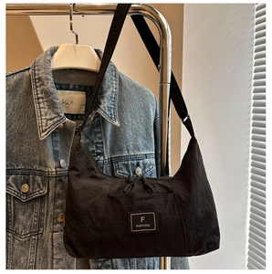 Detail of black nylon crescent hobo bag with logo patch hanging on a rack
