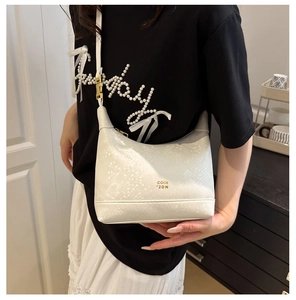 White dumpling bag with snake-skin texture and gold logo shown on model shoulder