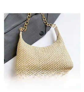 Detail of woven straw crescent bag with a gold chain strap and neutral cream texture