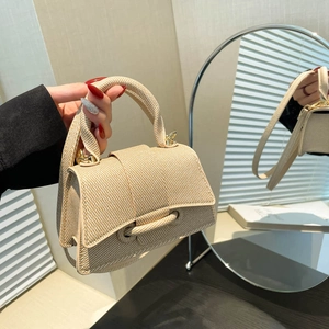 Sac à main beige tissé en forme de sablier avec base incurvée et détails dorés au miroir