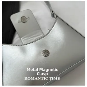 Close-up of silver metallic leather handbag featuring a magnetic hardware buckle closure