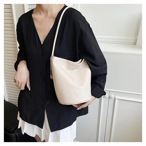 Detail of cream white litchi pattern leather bucket bag with silver chain accessory