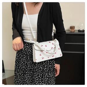 Detail of white PU leather crossbody bag with red cherry print and twisted rope handle