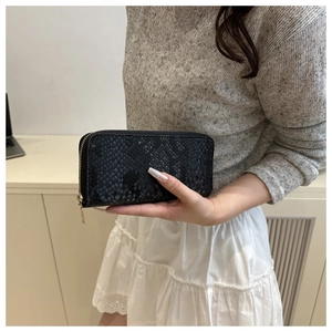 Close-up of black snake pattern wallet with gold zipper texture held by a person