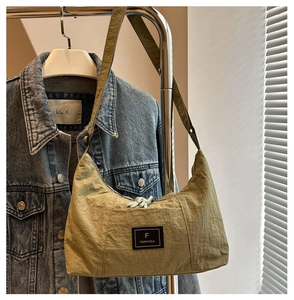 Detail of olive green crescent hobo bag featuring crinkled nylon and woven zipper puller