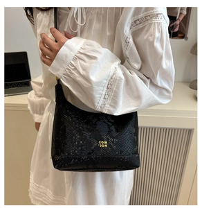 Close-up of black snake pattern texture and gold brand lettering on the hobo shoulder bag