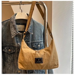 Close-up of khaki nylon tote bag with crinkled texture and signature brand label