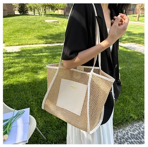 Close-up of woven straw tote bag with white leather straps and gold logo branding
