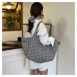 Macro detail of high-capacity black and white checkered canvas tote bag with soft texture