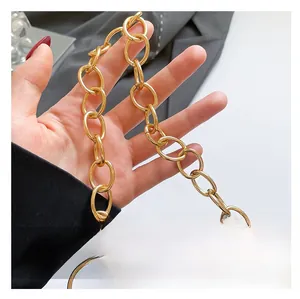 Detailed view of the gold oval metal chain handle on a summer straw tote bag