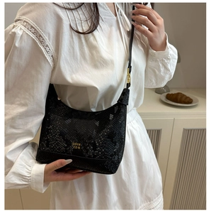 Detail of black snake-embossed hobo bag with gold logo on white dress model