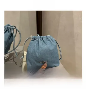 Gros plan du sac seau en jean avec cordon de serrage et logo en métal