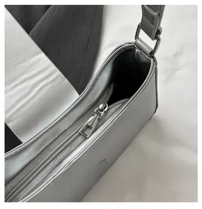 Detail view of smooth silver metallic zipper closure on textured faux leather underarm bag